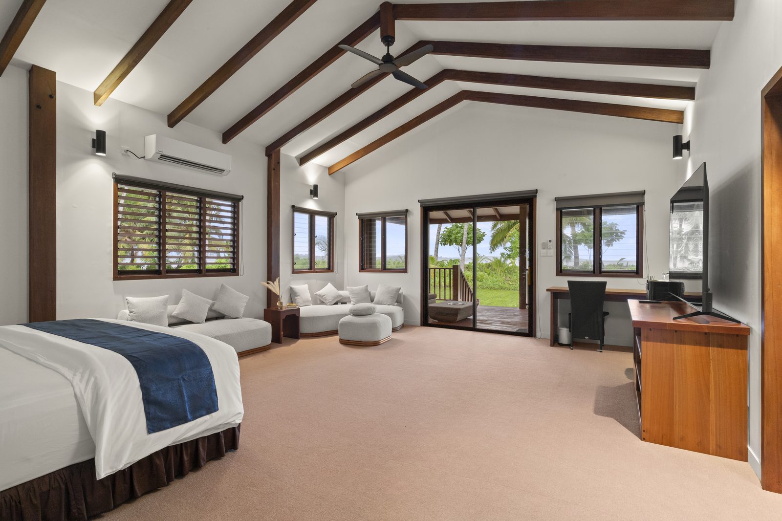 Ocean view suite at the Mega Villa, with king bed, lounge and glass doors opening to a palm-lined view